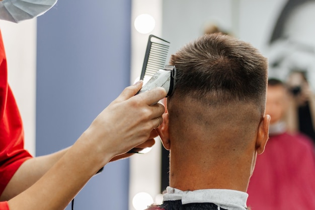 L'homme européen est coupé par un coiffeur Coiffure et coupe de cheveux pour hommes avec une tondeuse à cheveux dans un salon de coiffure ou un salon de coiffure