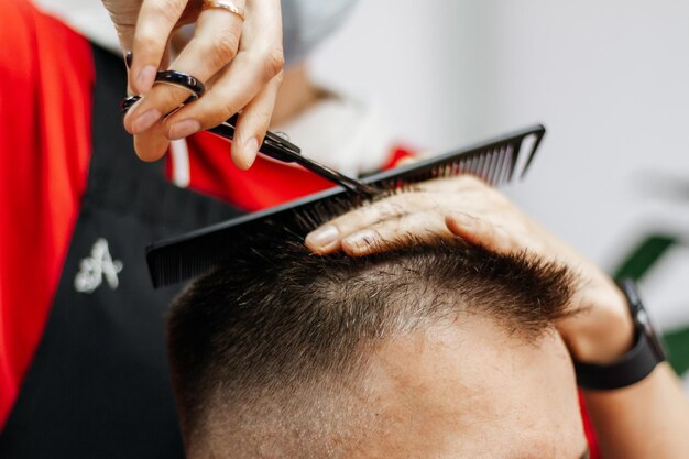 Un homme européen est coupé par un coiffeur Coupe de cheveux pour hommes avec des ciseaux dans le salon