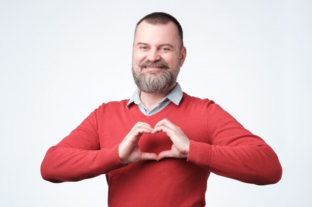 Homme européen mature avec barbe faisant du coeur des mains