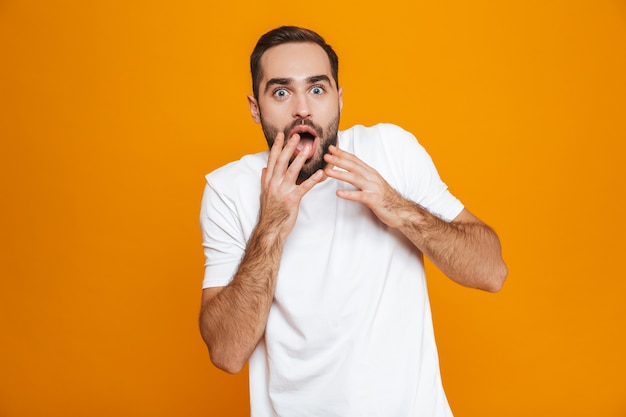 Homme excité avec barbe et moustache coning bouche en position debout, isolé sur jaune