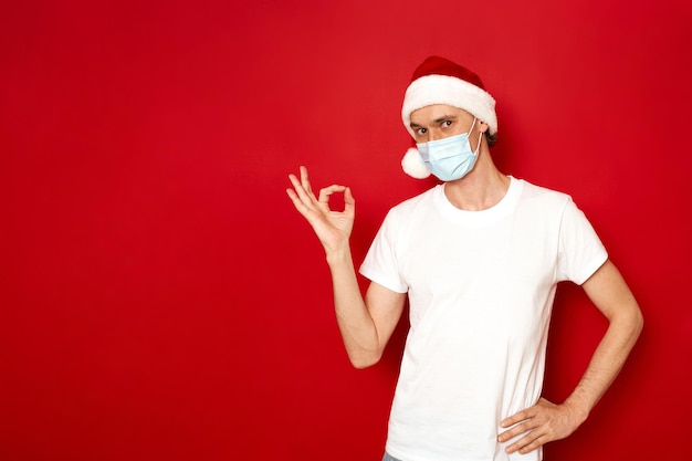 homme excité dans des vêtements décontractés Tshirt blanc montre un signe ok surligné un espace de fond rouge pour le texte