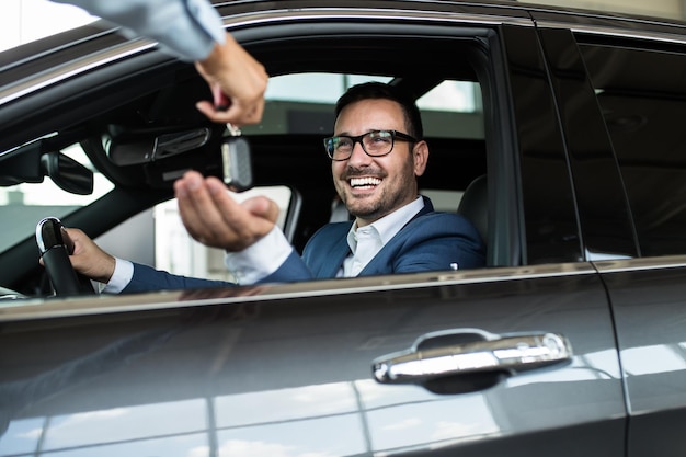 Homme excité heureux à cause de l'achat d'une nouvelle voiture.