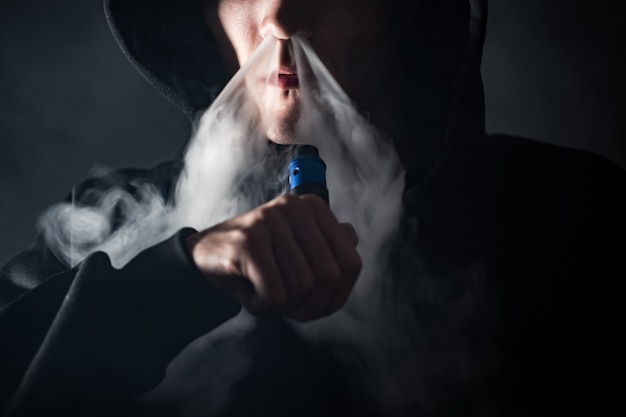 Un homme exhale un nuage de vapeur d'une cigarette électronique