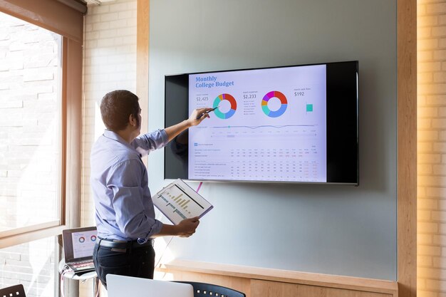 Homme expliquant le graphique sur écran plat au bureau