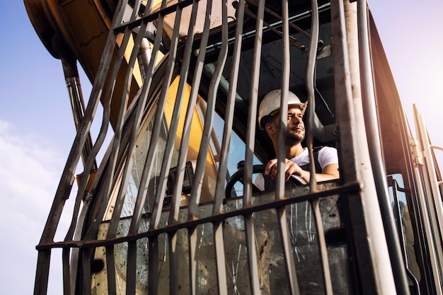 Homme exploitant une machine de levage de grue industrielle sur un chantier de construction.