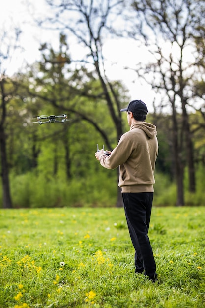 Homme d'exploitation de drone volant ou planant par télécommande dans la nature