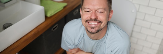 Un homme avec une expression faciale heureuse après les toilettes se sent mieux après avoir déféqué