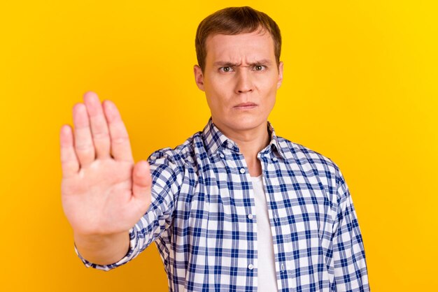 Homme expression faciale stricte sur fond jaune isolé faisant un geste d'arrêt avec sa main