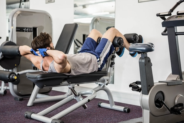 Homme faisant des abdominaux crunches sur un banc au gymnase