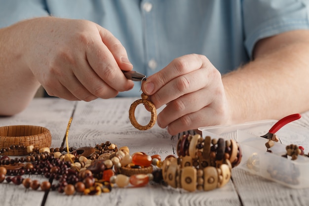 Homme faisant des boucles d'oreilles en bois artisanal