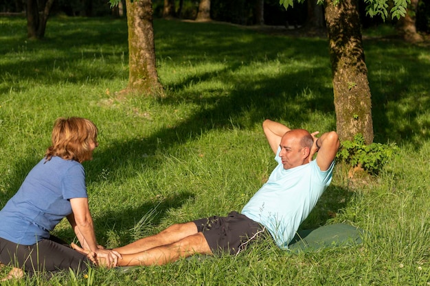 Homme faisant des craquements avec l'aide de sa femme pour être en forme et en bonne santé entouré par la nature