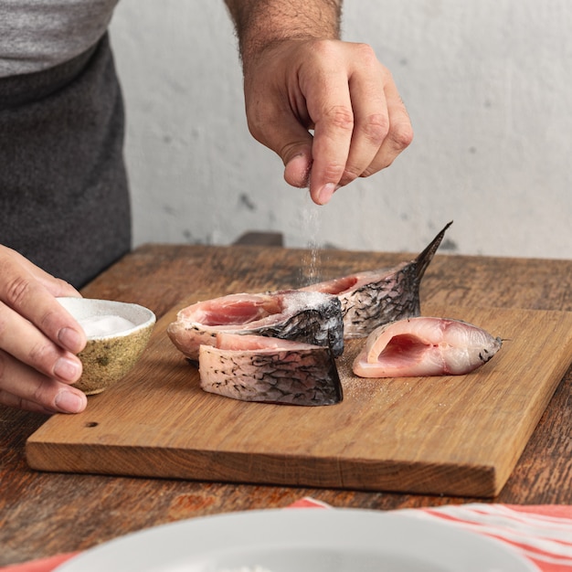 Homme faisant cuire du poisson à la maison dans la cuisine à domicile. Préparation d'un dîner savoureux et sain