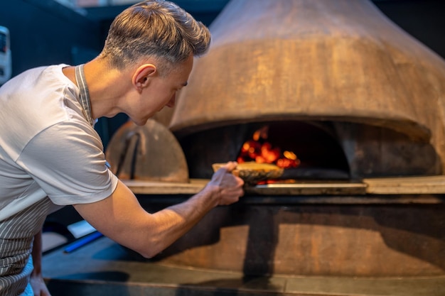 Un homme faisant du feu dans le four d'une boulangerie italienne