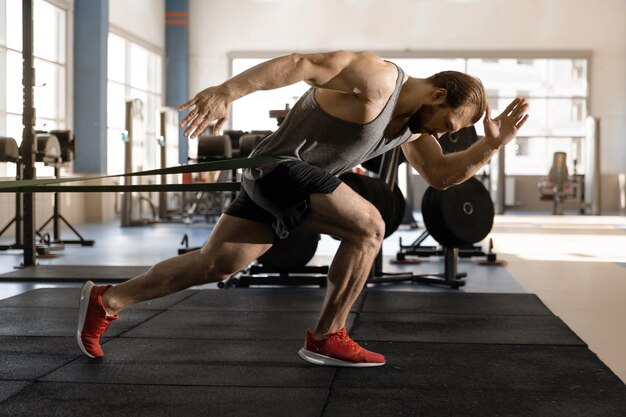 Homme faisant du jogging avec des élastiques tout en faisant de l'exercice dans la salle de sport