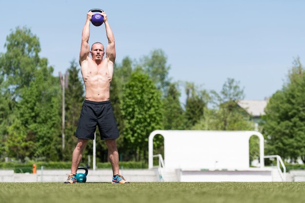 Photo homme faisant de l'exercice avec kettle bell à l'extérieur