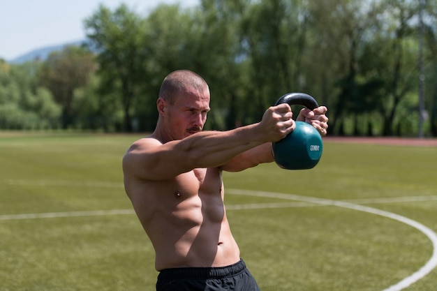 Homme faisant de l'exercice avec Kettle Bell à l'extérieur