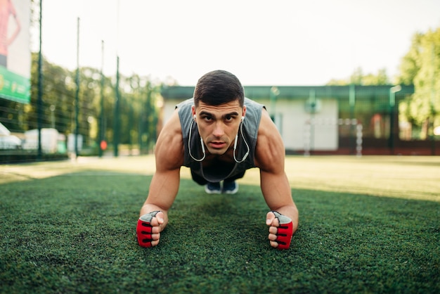 Homme faisant des exercices de push-up sur une herbe en plein air