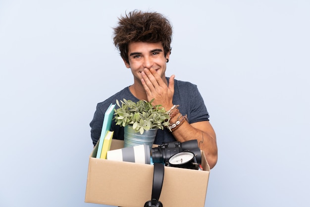 Homme faisant un geste tout en ramassant une boîte pleine de choses avec une expression faciale surprise