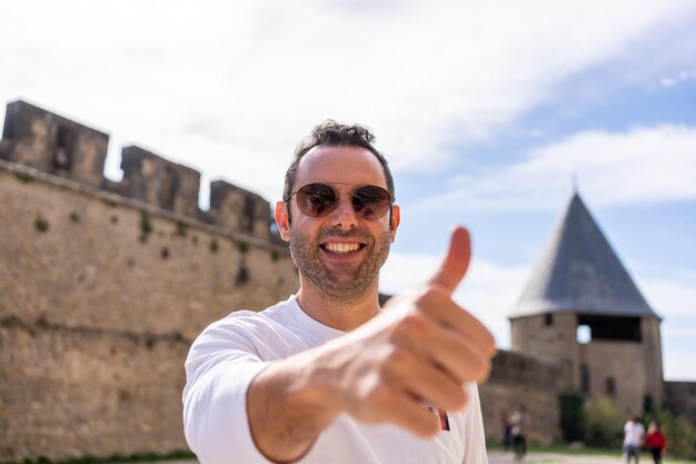 Homme faisant des gestes pour aller bien avec le doigt debout sur un château médiéval. Carcassonne France