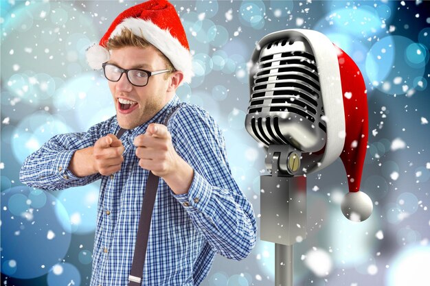 Homme faisant des gestes vers le microphone avec bonnet de Noel sur fond généré numériquement