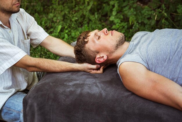 Homme faisant un massage ostéopathique de la tête et du cou dans la nature 3