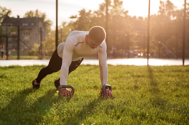 Un homme faisant des pompes sur un terrain en herbe.