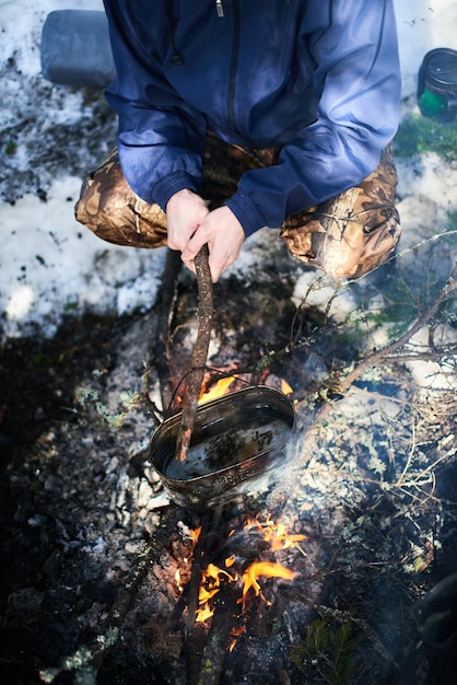 L'homme fait bouillir la marmite sur le feu