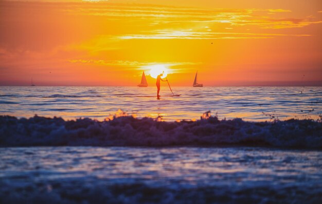 Un homme fait du paddle pendant un beau lever de soleil Coucher de soleil sur la mer Lever de soleil sur la plage