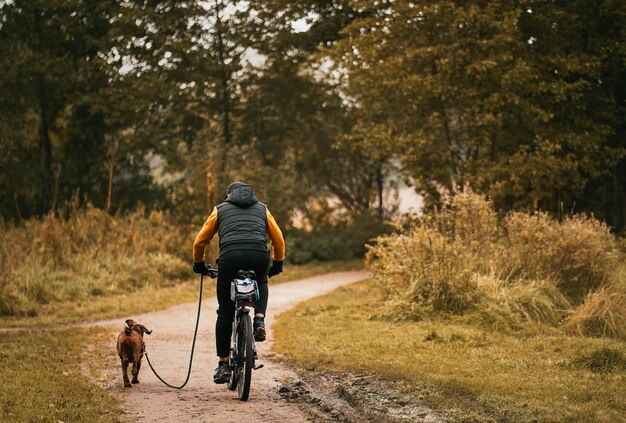 L'homme fait du vélo dans le parc avec son chien