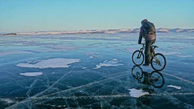 L'homme fait du vélo sur la glace Glace du lac Baïkal gelé