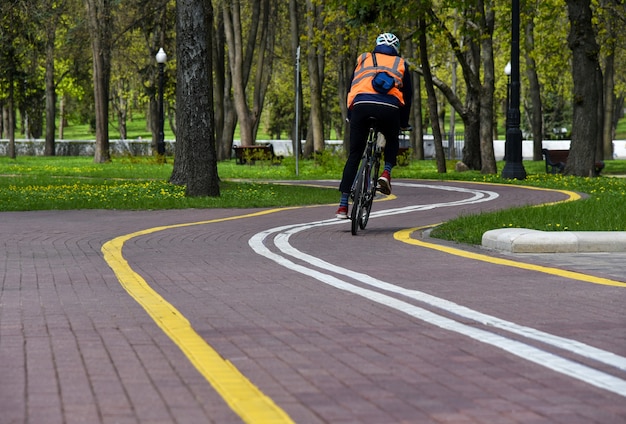 Un homme fait du vélo sur une piste cyclable dans un parc.