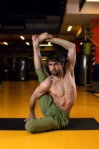 Un homme fait du yoga et regarde la caméra.