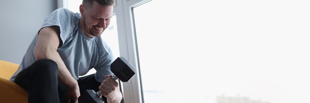 L'homme fait des exercices avec des haltères pour les biceps