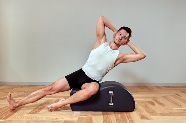 Un homme fait des exercices sur un réformateur de pilates réformateurs pour la gymnastique de pilates