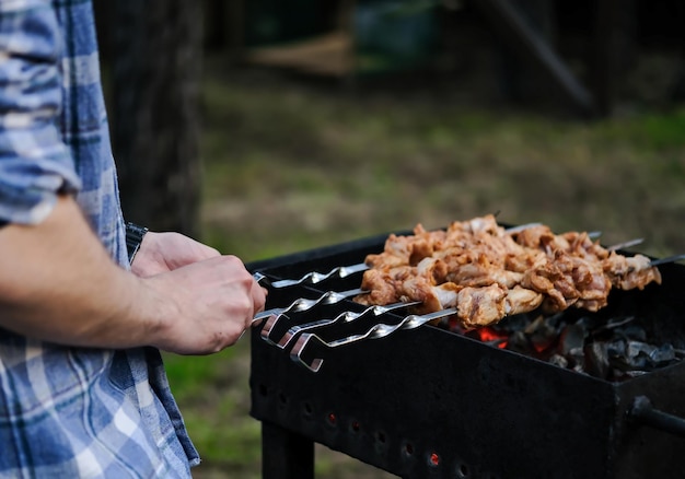 Un homme fait frire un barbecue de viande sur des charbons Viande grillée sur des charbons Poulet BBQ Viande grillée