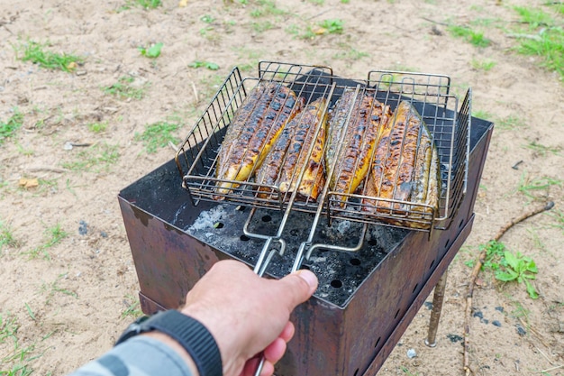 Un homme fait griller un gril avec une fourchette et une main tient un gril.