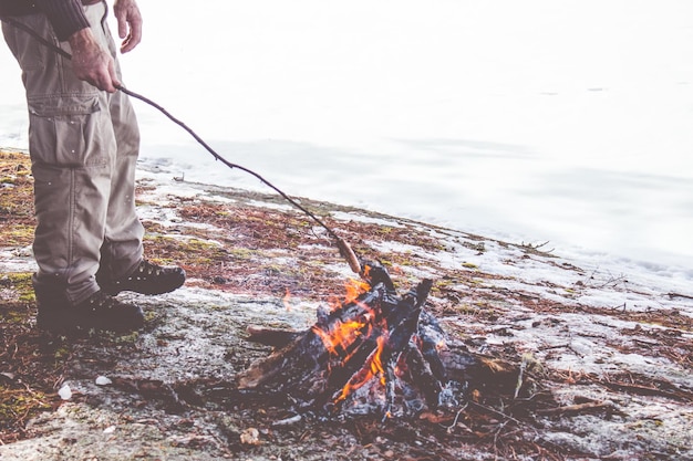 Un homme fait des saucisses sur un feu ouvert.