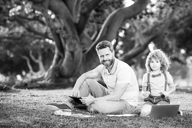 Photo homme de famille affaires en ligne père et fils travaillant sur ordinateur portable à distance dans le parc