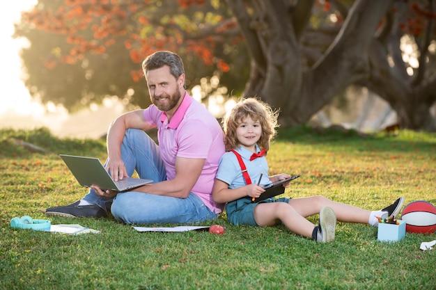 Homme de famille en ligne père et fils travaillant sur une télécommande pour ordinateur portable dans le parc