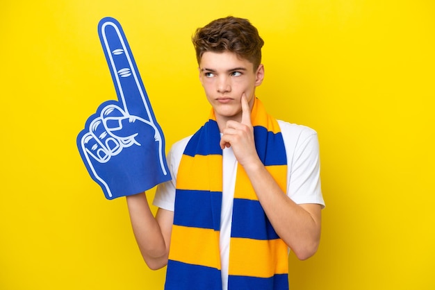 Homme fan de sport adolescent isolé sur fond jaune pensant à une idée tout en levant les yeux