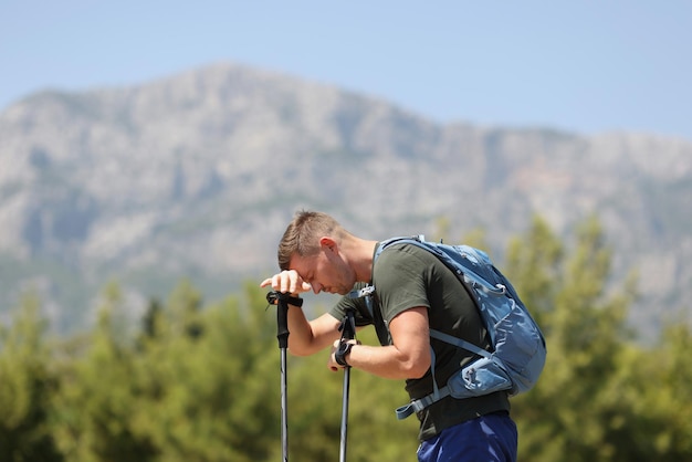 Homme fatigué avec des bâtons de marche scandinaves sur les avantages et les inconvénients de la marche nordique en montagne