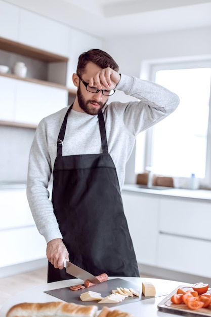 L'homme fatigué fait des sandwichs dans sa cuisine