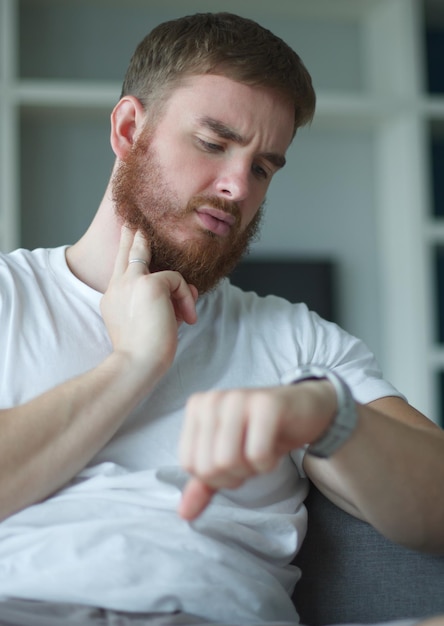 Homme fatigué mesurant le pouls de la fréquence cardiaque avec les doigts sur son cou et regardant la montre de sport à