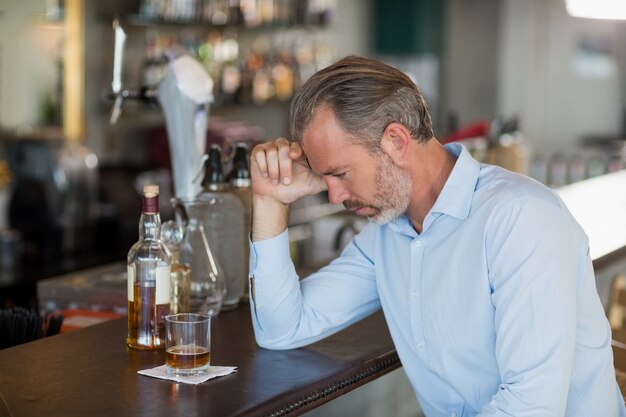 Homme fatigué, penchant son coude sur le comptoir