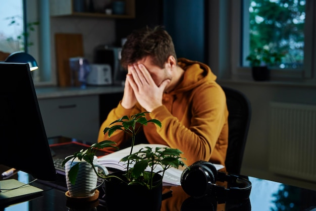 L'homme fatigué travaille tard au lieu de travail pendant la nuit