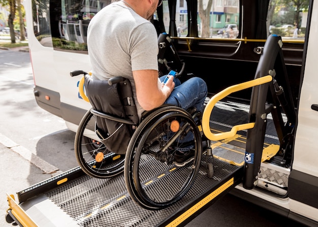 Un homme en fauteuil roulant sur un ascenseur d'un véhicule pour personnes handicapées