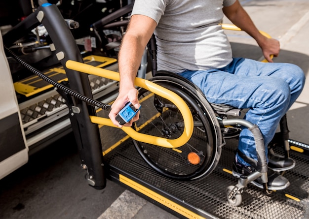 Un homme en fauteuil roulant sur un ascenseur d'un véhicule pour personnes handicapées.