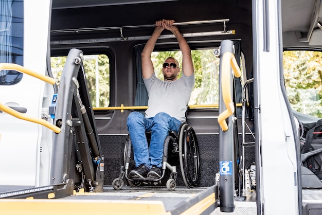 Un homme en fauteuil roulant sur un ascenseur d'un véhicule spécialisé pour les personnes handicapées.