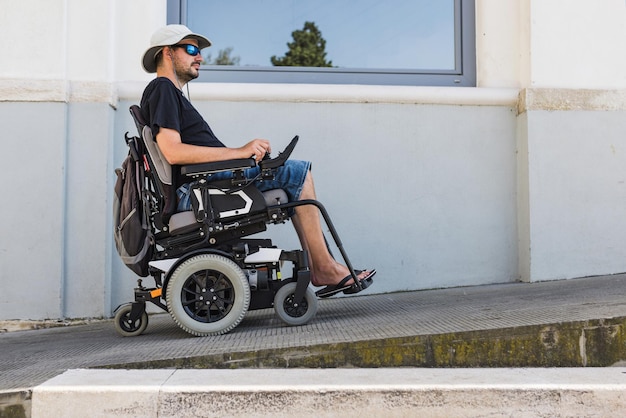 Un homme en fauteuil roulant électrique utilisant une rampe d'accès au bâtiment dans un logement de vacances d'été