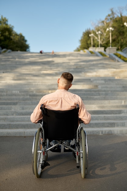 Homme en fauteuil roulant à l'escalier, vue arrière